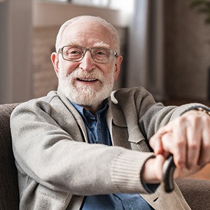 Happy senior man resting his hands on cane