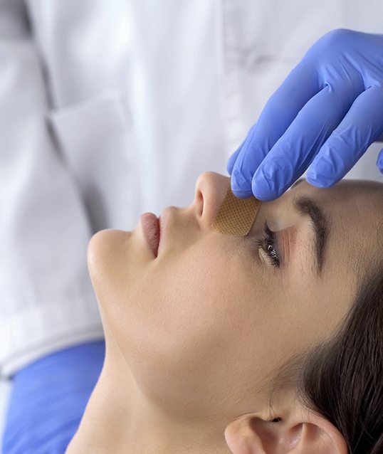 Cosmetic surgeon touching a patient’s nose