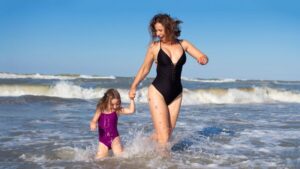 Attractive mom playing on the beach with her daughter