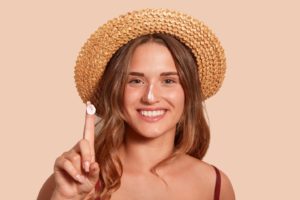 Woman wearing a hat and sunscreen to protect nose after rhinoplasty